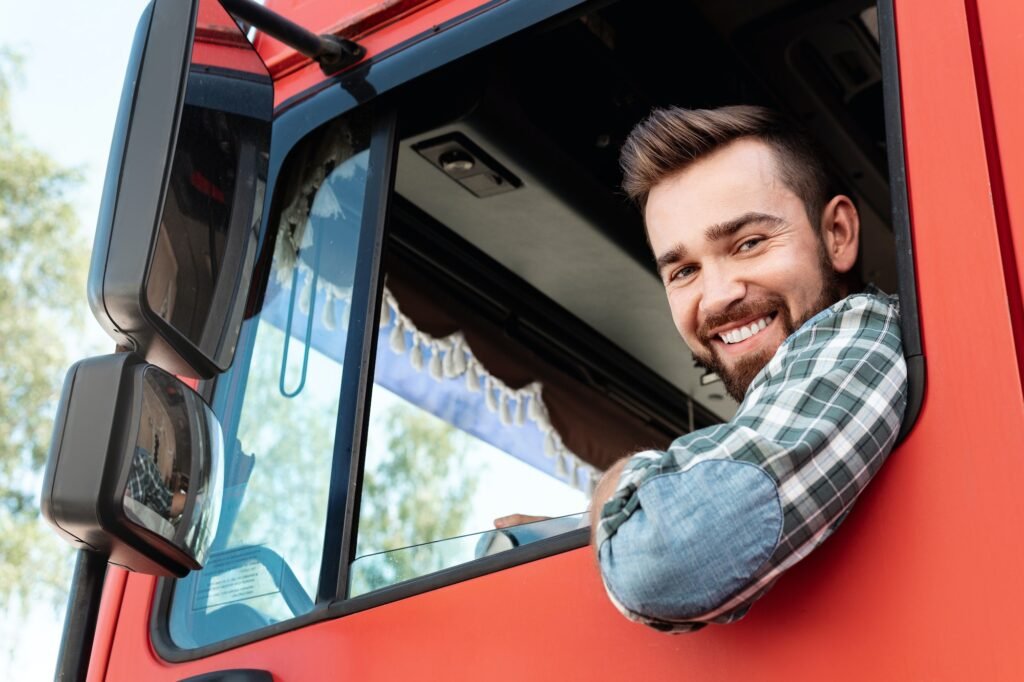 Happy male truck driver inside his red cargo truck