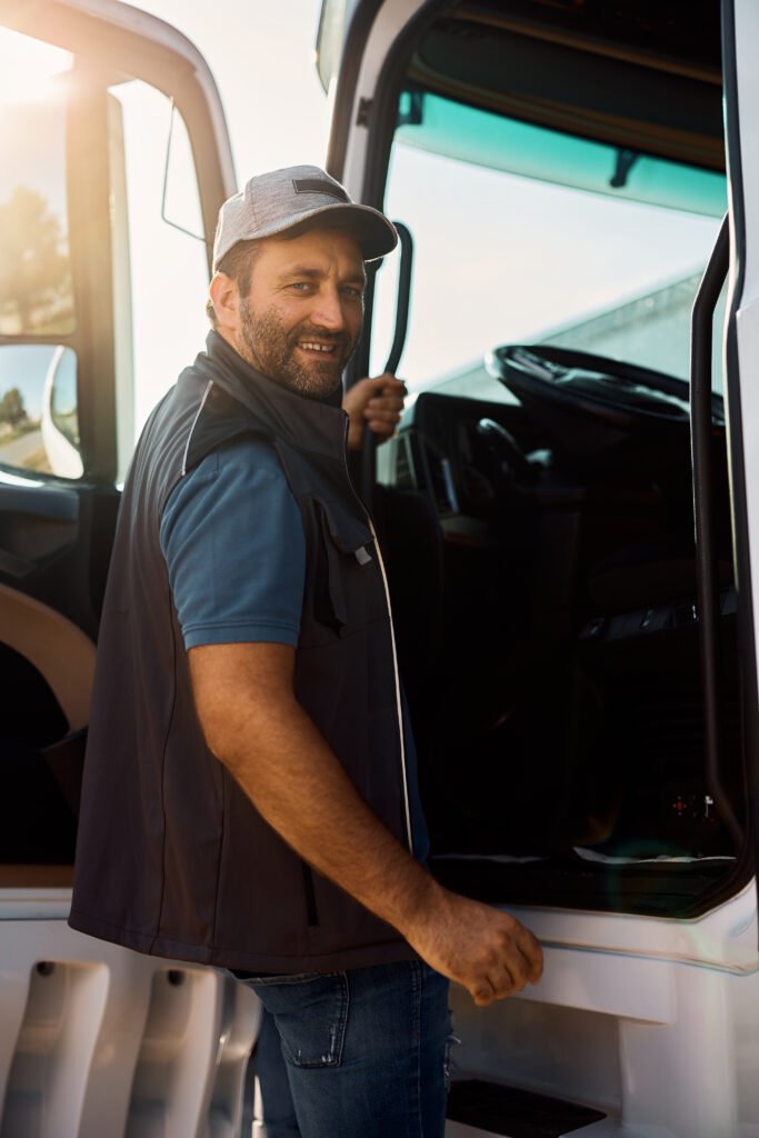 Happy truck driver getting into vehicle cabin and looking at camera.